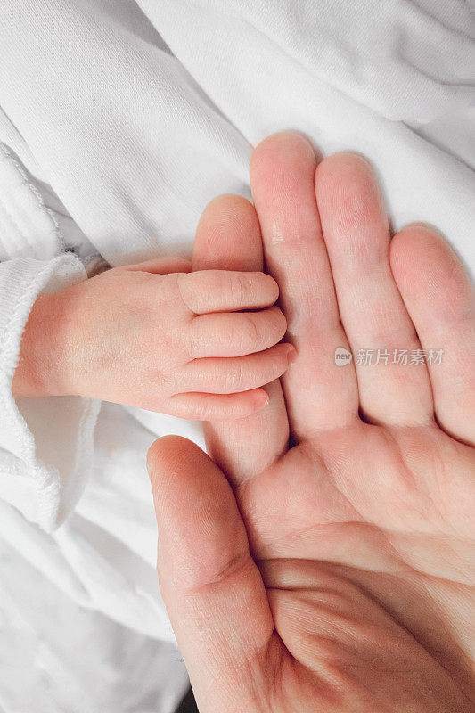 新生儿握着父亲的手指。新生女儿的小手放在dadâ的手上。特写镜头。